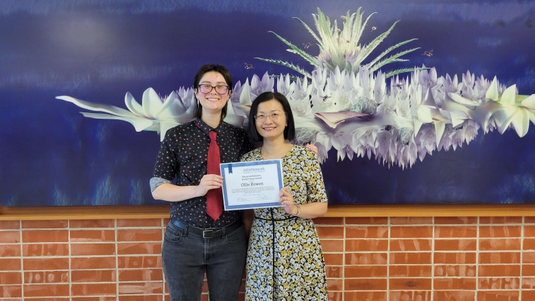 A student and a faculty member pose for a photo with an award.